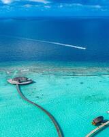 scenario paradisiaco delle maldive. paesaggio aereo tropicale, paesaggio marino con lungo molo, ville sull'acqua con splendida spiaggia di mare e laguna, natura tropicale. banner di destinazione turistica esotica, vacanze estive foto