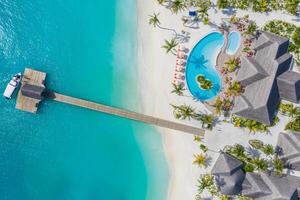 bella veduta aerea del bordo piscina e della spiaggia del resort con molo in legno. lussuoso paesaggio da spiaggia tropicale, nuoto, sedie a sdraio e lettini, ombrelloni. spiaggia tropicale, vista dall'alto del drone aereo foto