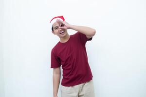 giovane asiatico uomo indossare un' Santa Claus cappello con un' mano fabbricazione il ok gesto isolato di un' bianca sfondo per visivo comunicazione foto