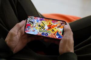 Pokemon partire mobile ios gioco su i phone 15 smartphone schermo nel maschio mani durante mobile gameplay foto