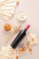 bottiglia di rosso kosher vino, matzoth pane, Noci, frutta mescolare su beige sfondo. tradizionale cibo per il ebraico Pasqua ebraica vacanza. verticale Visualizza. foto