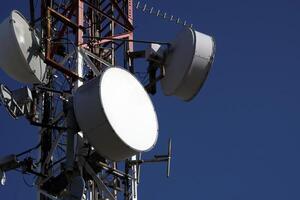 telecomunicazione antenna con multiplo satellitare piatti contro il blu cielo foto