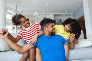 amorevole diverso genitori trascorrere tempo con poco adorabile figlia avere divertimento insieme a moderno casa sorridente ridendo, vicino su. contento multietnico famiglia concetto foto