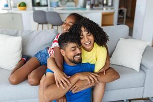 contento famiglia madre padre e bambino figlia ridendo e havig divertimento a casa. contento africano americano famiglia rilassante foto