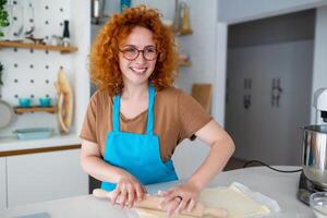 cottura al forno concetto. ritratto di gioioso donna impasto Impasto nel cucina interno, allegro femmina nel grembiule avendo divertimento mentre preparazione fatti in casa Pasticcino, foto