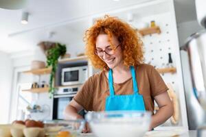 contento attraente giovane adulto donna casalinga panettiere indossare grembiule Tenere perno rotolamento Impasto su cucina tavolo cottura al forno Pasticcino concetto cucinando torta biscotto fare forno fabbricazione fatti in casa Pizza a casa foto