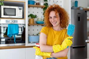 giovane donna fare Casa faccende Tenere pulizia Strumenti. donna indossare gomma da cancellare protettivo giallo guanti, Tenere straccio e spray bottiglia detergente. è mai pure in ritardo per pulito foto