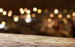 vuoto legna tavolo superiore su sfocatura leggero oro bokeh di bar ristorante nel buio sfondo foto