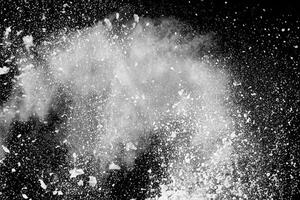 forme bizzarre di nuvola di esplosione di polvere bianca su sfondo nero. schizzi di particelle di polvere bianca. foto