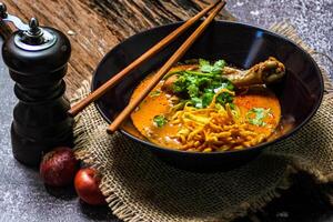 khao così io ricetta khao soi, Khao così io kai, tailandese tagliatelle khao così io, pollo curry con stagionatura su di legno pavimento, settentrionale tailandese cibo concetto. lanna cibo foto