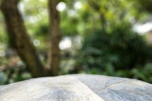 pietra tavolo con sfocato giardino sfondo, adatto per Prodotto presentazione sfondo, Schermo, e finto su. foto