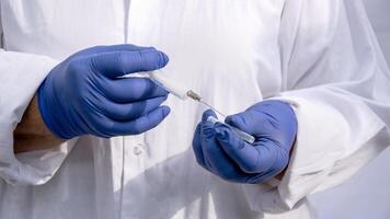 il medico mani nel blu guanti hold il ago di un iniezione siringa. foto