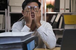 esausto giovane uomo con il computer portatile nel ufficio. foto