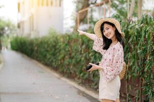 ritratto di asiatico giovane donna viaggiatore con tessitura cappello e cestino contento Sorridi su verde pubblico parco natura sfondo. viaggio viaggio stile di vita, mondo viaggio esploratore o Asia estate turismo concetto. foto