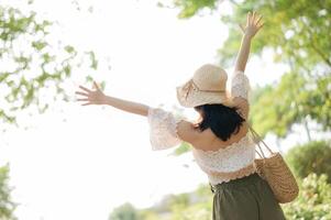 ritratto di asiatico giovane donna viaggiatore con tessitura cappello e cestino e un' telecamera su verde pubblico parco natura sfondo. viaggio viaggio stile di vita, mondo viaggio esploratore o Asia estate turismo concetto. foto