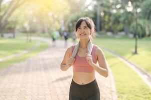 in forma contento Sorridi 30s giovane asiatico donna nel abbigliamento sportivo gode rinfrescante tramonto correre nel natura. il silhouette di figura contro il ambientazione sole è bellissimo vista. fitness, Salute, o motivazione concetto. foto