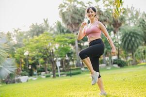 concetto di benessere e benessere in forma 30s asiatico donna indossare rosa abbigliamento sportivo esercizio nel pubblico parco a tramonto. salutare all'aperto stile di vita, benessere e benessere. foto