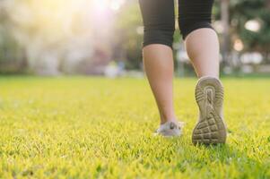 jogger donna. vicino su persona formazione sport corridore giovane femmina scarpa su erbe nel pubblico parco. fitness gamba e piede esercizio atleta. maratona nel natura. attivo salutare stile di vita allenarsi concetto. foto