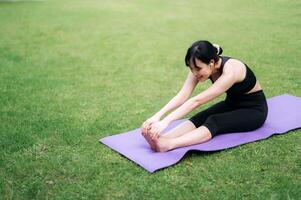 ritratto in forma giovane 30s asiatico donna nel rosa abbigliamento sportivo con yoga stuoia. allungamento muscoli nel parco. abbraccio benessere nel natura con jogger praticante yoga nel natura, promozione Salute e consapevolezza. foto