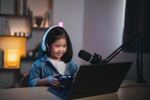 asiatico influencer giovane ragazza Sorridi allegro utilizzando telecomando da gioco giocando gioco vivere streaming saluto video conferenza con il computer portatile e indossare cuffia. bambini streaming getto gioco in linea concetto. foto