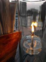 olio lanterna scrivania lampada, trasparente bicchiere, romantico leggero su il di legno tavolo, caldo umore ristorante, vicino su, cenare tavolo ambientazione con fazzoletto di carta carta per cliente foto