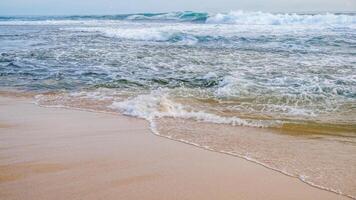 onde Crashing su il bianca sabbia spiaggia foto