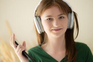 ritratto di adolescenziale ragazza ascoltando per musica con cuffie e mobile Telefono. foto