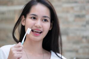ritratto di un' giovane asiatico donna con bretelle su sua denti foto