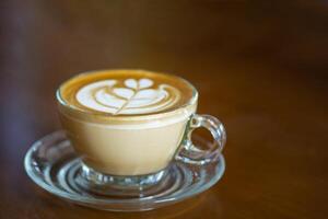 avvicinamento di caffè tazza con cuore forma latte macchiato arte schiuma su di legno tavolo. foto