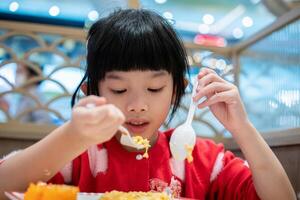 carino poco asiatico bambino ragazza mangiare cibo foto