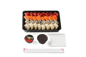 un' impostato di Sushi nel un' consegna scatola, soia salsa, bacchette, wasabi, Zenzero su un' bianca sfondo foto