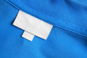 vuoto bianca lavanderia cura Abiti etichetta su blu camicia tessuto struttura sfondo foto