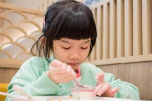carino poco asiatico bambino ragazza mangiare cibo foto