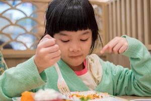 carino poco asiatico bambino ragazza mangiare cibo foto