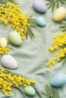 colorato Pasqua uova e mimosa fiori su verde tessile sfondo. foto