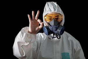 donna in abbigliamento protettivo chimico e maschera antigas con occhiali su sfondo bianco, scienziata in tuta di sicurezza, concetto di infezione da virus di sicurezza foto