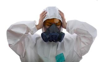 la donna si sente affaticata in un abbigliamento protettivo chimico e maschera antigas con occhiali gialli su sfondo bianco, scienziate in tuta di sicurezza foto