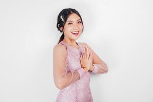 amichevole asiatico donna indossare rosa vestito è dando gesti di tradizionale saluti di sua mani foto