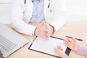 medico e paziente stanno discutendo qualcosa, solo le mani al tavolo, l'assicurazione medica.