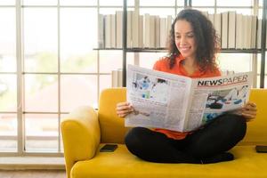 America latina donna che legge il giornale sul divano foto