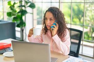 donna latina che lavora con una tazza di caffè sullo spazio di lavoro foto