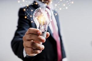 idea e concetto di innovazione tecnologica, uomo d'affari che tiene in mano una lampadina che brilla con la linea di collegamento del potere