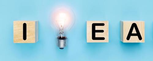 idea e nuovo concetto di pensiero creativo, lampadina con parola idea su blocco di legno su sfondo blu foto