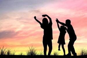 silhouette di famiglia, mamma e papà, i genitori portano la figlia o la ragazza a ballare al tramonto perché hanno tempo libero, si rilassano e hanno una giornata divertente e felice. foto