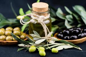 olio d'oliva spremuto a freddo con ramo e frutti foto