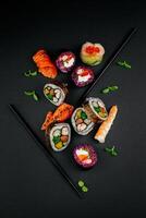 Sushi impostato con caviale, avocado e salmone. Sushi pezzi posto fra bacchette, separato su nero sfondo. asiatico cucina. superiore Visualizza. gratuito spazio per il tuo testo. alto qualità foto