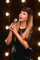 giovane faccina bella ragazza dai capelli lunghi con microfono che canta una canzone sul palco del karaoke