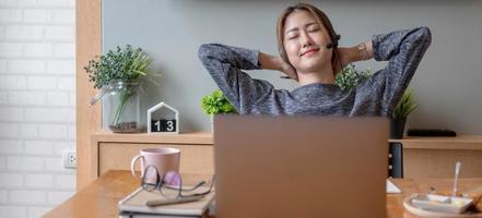 ritagliata colpo sorridente freelance donna asiatica che indossa l'auricolare, comunicando con il cliente tramite chiamata computer video. tutor femminile professionale millenario piacevole che tiene lezioni di lingua online foto