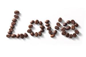 segno di amore con chicchi di caffè disposti su sfondo bianco. foto