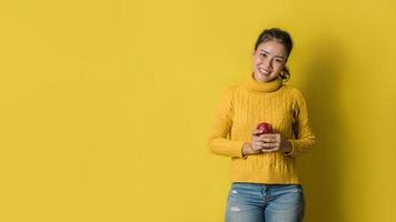 allegra giovane donna su sfondo giallo in studio con una mela rossa in mano. il concetto di esercizio per una buona salute. amante della salute foto